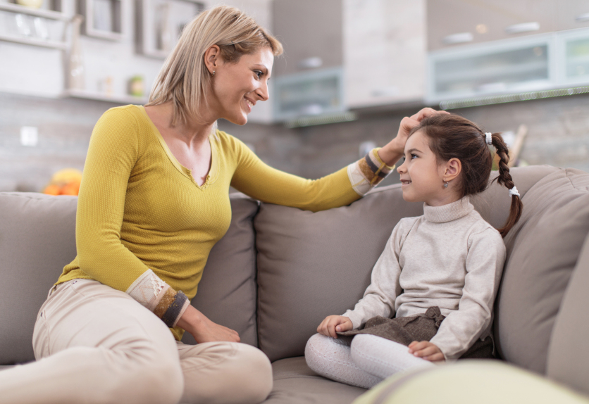 Happy mother talking to her daughter at home.